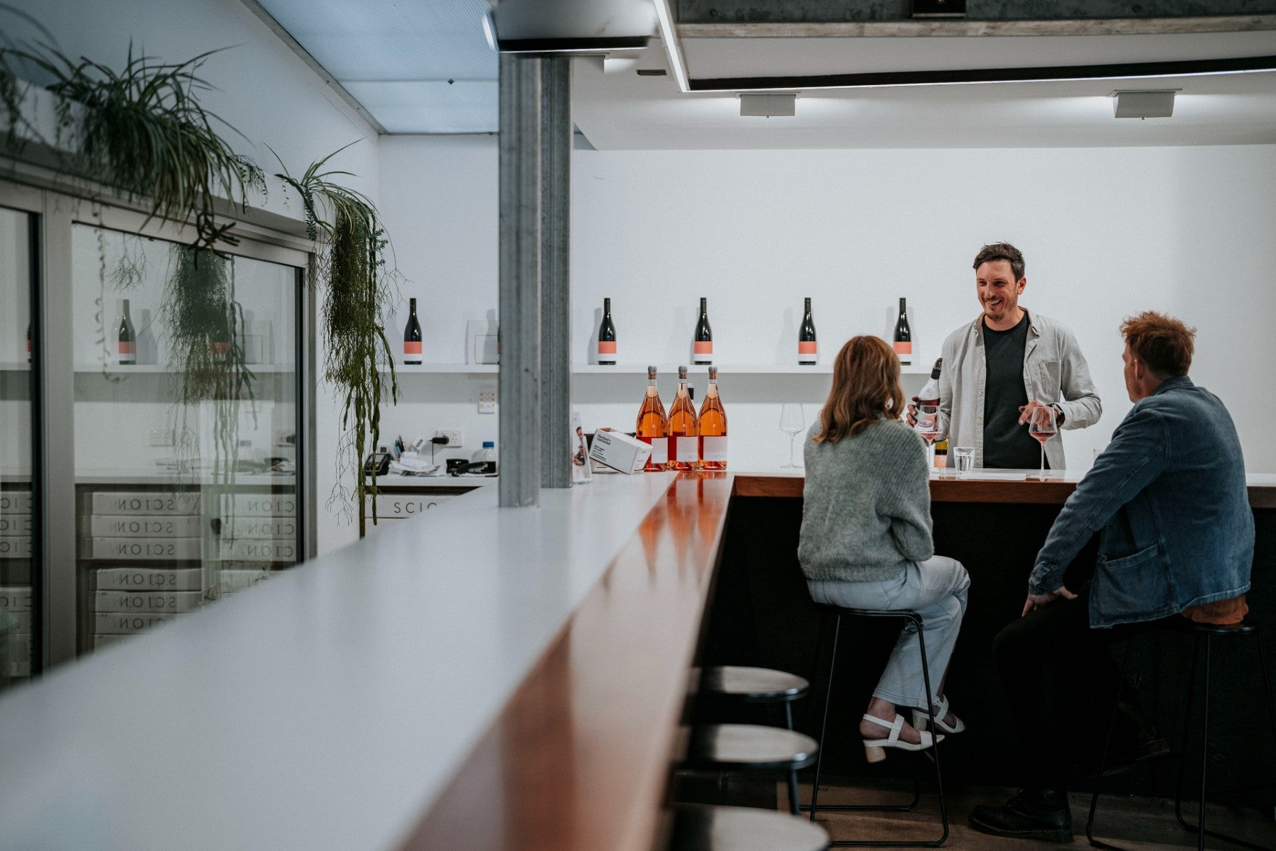 Man behind bar pours wine for seated couple