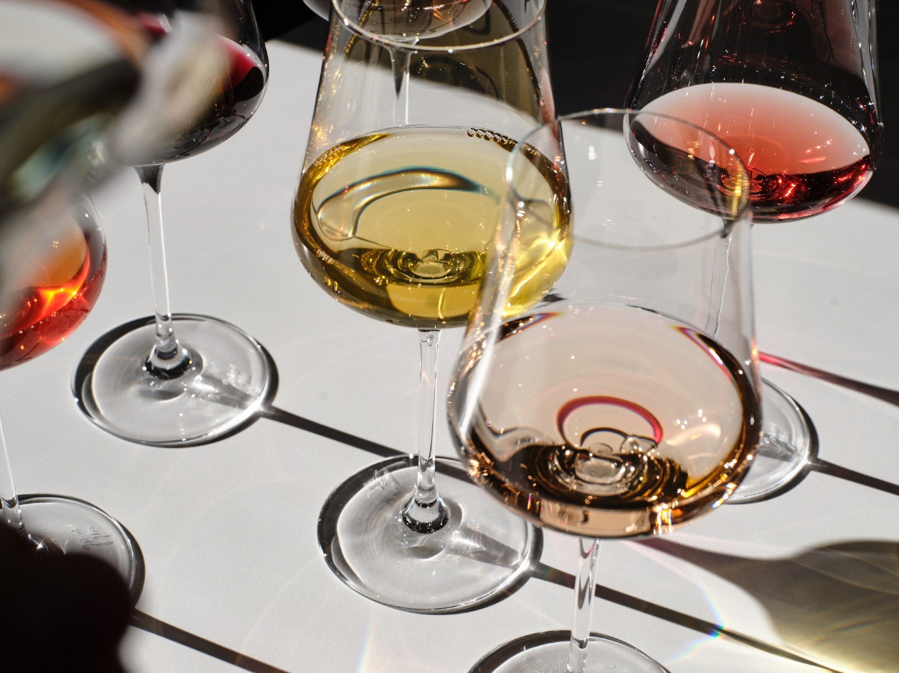 Close-up of wine glasses with different types of wine on a reflective surface